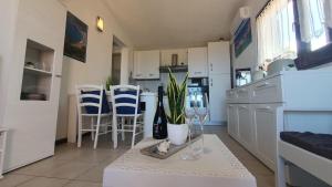 a kitchen with white cabinets and a table with wine glasses at Poolvilla Bellavista - Vista Panoramica sul Mare in Costa Paradiso