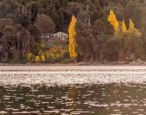 a large body of water with a house in the background at Hosteria El Condado in San Carlos de Bariloche