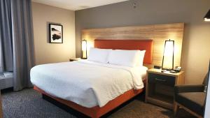 a hotel room with a large bed and a chair at Candlewood Suites Sheridan by IHG in Sheridan +52 photos