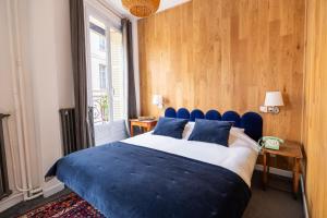 a bedroom with a blue bed and a window at Hôtel d'Angleterre in Versailles
