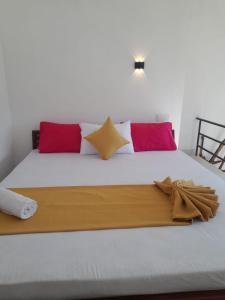a white bed with red and white pillows on it at Sunshine Holiday Inn Ella in Ella