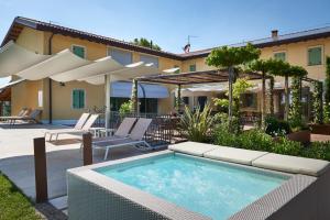 a pool with chairs and umbrellas on a patio at Country Resort Canova in Negrar