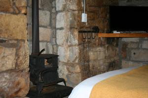 a bedroom with a stone wall with a wood stove at John Jack Inn Accommodation in Chrissiesmeer