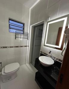 a bathroom with a sink and a toilet and a mirror at Loft Moderno Goēde in Pomerode