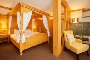a bedroom with a canopy bed and a chair at Flair Hotel Vier Jahreszeiten in Bad Urach +133 photos