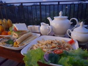 a table topped with dishes of food and a salad at Sunshine Holiday Inn Ella in Ella +29 photos