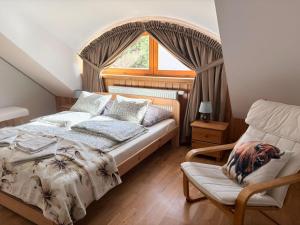 a bedroom with a bed and a chair and a window at Dębowa Dziupla in Białowieża
