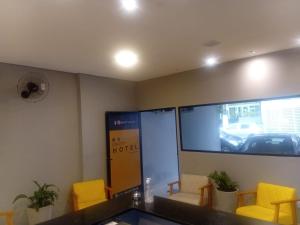 a waiting room with yellow chairs and a large screen at Unity Hotel - Allianz SP in São Paulo