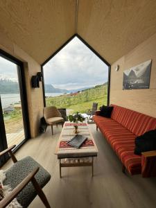 a living room with a red couch and large windows at Cabin in the orchard in Sandane
