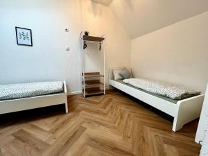 two beds in a room with wooden floors at modernes Apartment mit Wlan in Lorsch