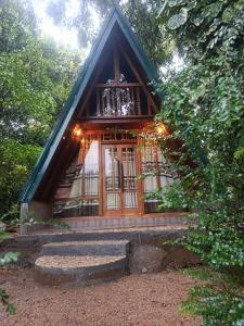 a small cabin with a glass door in a forest at Velya cabana in Belihuloya