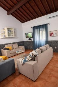 a living room with two couches and a television at Cantinho do Sol in Mosteiros