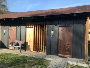 a building with two doors and a bench on a patio at Chalmová CHATA 27 in Bystričany