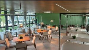 a restaurant with tables and chairs and a green wall at Beach Class Verano - Resort em Muro Alto por Yolo in Ipojuca