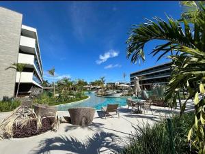 a swimming pool with chairs and tables and a building at Beach Class Verano - Resort em Muro Alto por Yolo in Ipojuca