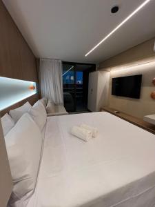 a bedroom with a large white bed with a flat screen tv at Beach Class Verano - Resort em Muro Alto por Yolo in Ipojuca +35 photos