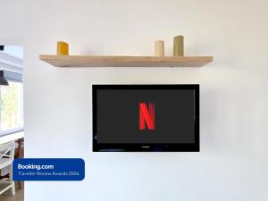 a flat screen tv on a wall with a wooden shelf at Apartman Point in Štrba +7 photos