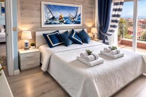 a bedroom with a large white bed with towels on it at Due Passi dal Cielo Apartment Piscina Condominiale fino al 30 Agosto in Anzio +13 photos