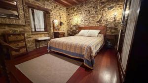 a bedroom with a bed and a stone wall at Rego de Cora By Oktheway in Valcarría