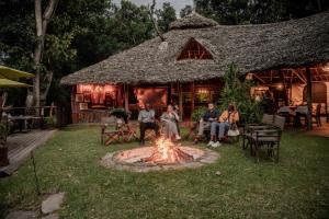 a group of people sitting around a fire in a yard at Exploreans Mara River Camp in Musiara Campsite