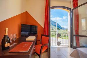 a room with a desk with a bottle of wine and a window at Hotel al ritrovo in Castelluzzo