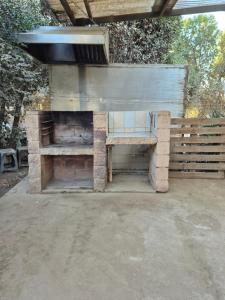 a stone fireplace with a bench under a roof at Casa Montes Valle Alegre in Quintero