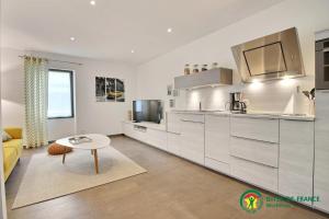 a kitchen with white cabinets and a table at Ty moncher côté cour in Plouhinec