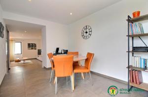 a dining room with a table and chairs and a clock at Ty moncher côté cour in Plouhinec