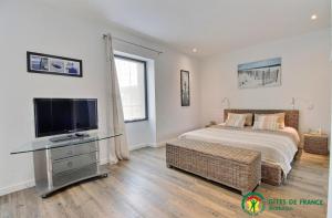 a bedroom with a bed and a flat screen tv at Ty moncher côté cour in Plouhinec
