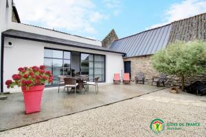 a home with a patio with a table and chairs at Ty moncher côté cour in Plouhinec