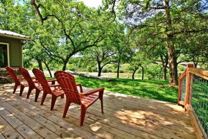 a row of chairs sitting on a wooden deck at Frog Cottage on the Blanco in Wimberley
