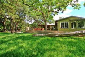 a house with a large tree trunk in the yard at Frog Cottage on the Blanco in Wimberley