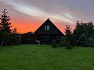 a house on a field with a sunset in the background at Melbury Chalet in West Stour