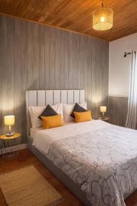a bedroom with a large bed with two lamps at Cantinho do Sol in Mosteiros
