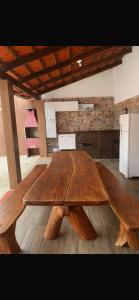 a large wooden table in a room with a refrigerator at Suítes Goiabal in Pirenópolis