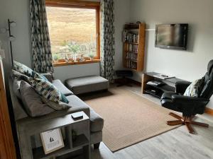 a living room with a couch and a chair and a television at Apartment 2, Craigmore, Upper Baila, Lerwick in Lerwick