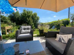 a patio with two chairs and a table with an umbrella at Villa Thorens in Morlaix
