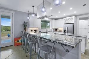 a kitchen with white cabinets and a large island with bar stools at Gatlin Getaway in Dripping Springs