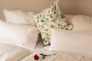 a bed with white pillows and a red rose on it at Hotel Jesteburger Hof in Jesteburg