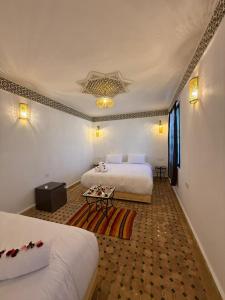 a hotel room with two beds and a table at Riad Mira in Fez