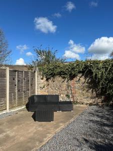 a black bench sitting in front of a brick wall at The Garden Haven in Cheddar