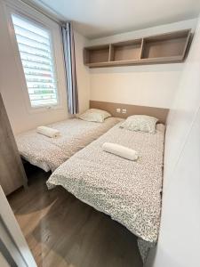 two beds in a small room with a window at Chez Maxime - E33 - Clim TV Lave-vaisselle - Proche Europa Park et Rulantica in Boofzheim