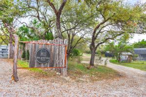 a wooden gate with a sign on it next to trees at Good Day Treehouse in Wimberley