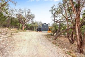 a dirt road leading to a black barn at Good Day Treehouse in Wimberley +50 photos