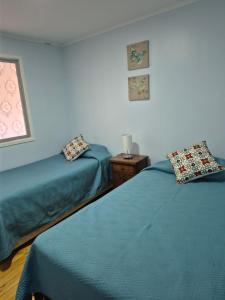 a room with two beds and a table and a window at Casa Montes Valle Alegre in Quintero
