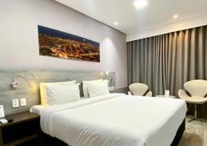 a hotel room with a large white bed in it at Nord Luxxor Citymix in Campina Grande