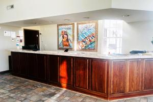a large wooden counter in a room with paintings on the wall at Osage Village Inn Near Lake Ozarks US 54 in Osage Beach +39 photos