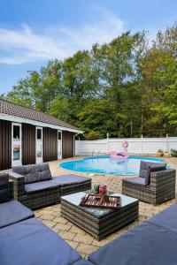 a backyard with a pool with couches and a person swimming at BL1163-Blokhus-Raappenmark-2 in Blokhus