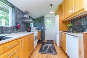 a kitchen with wooden cabinets and a kitchen rug on the floor at VGO922-Grabo-Strandkullen-22 in Gråbo +3 photos