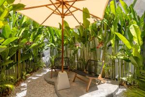 two chairs and an umbrella in a garden at Brisa Lofts Uluwatu in Uluwatu